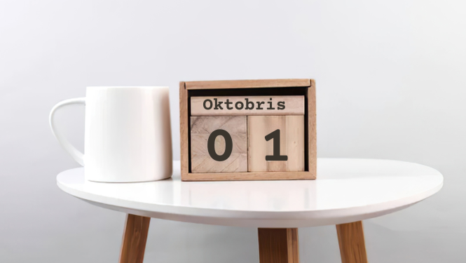 Balts žurnālgads ar baltu krūzi un koka kalendāru ar uzrakstu 01. oktobris