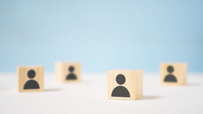 Zils fons ar četriem koka klucīšiem, kuriem virsū uzzīmēti cilvēku torsi