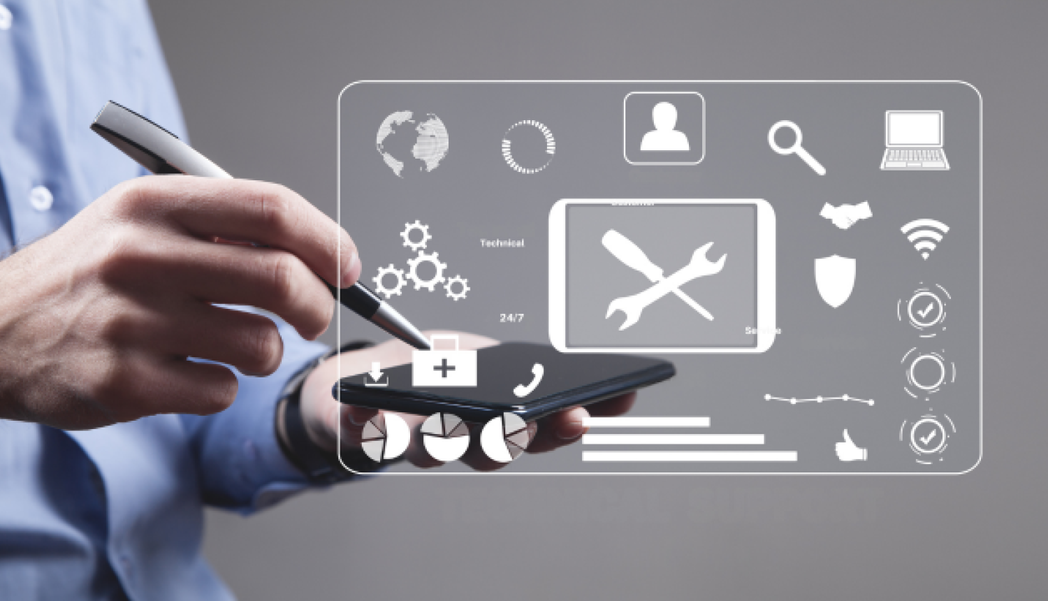 Cilvēks gaiši zilā kreklā tur viedtālruni un ar irbuli pieskaras ekrānam. Virs tālruņa redzams caurspīdīgs digitālais interfeiss ar tehniskā atbalsta un servisa ikonām, piemēram, sakrustotu uzgriežņu atslēgu un skrūvgriezi, zobratiem, globusu, telefona klausuli un datu diagrammām.