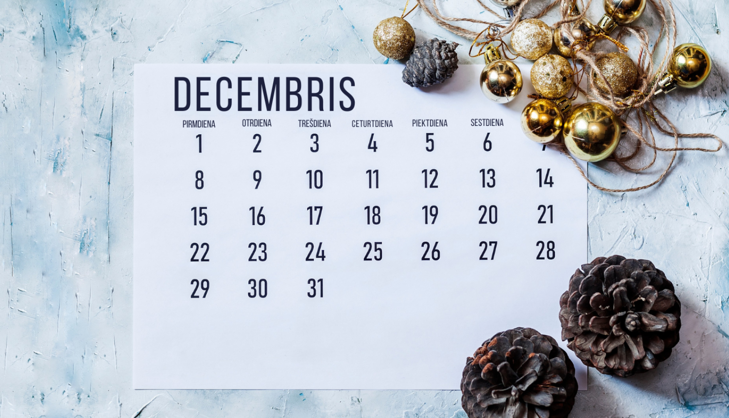 Decembra kalendāra lapa uz kuras čiekuri un zeltītas eglīšu rotājums